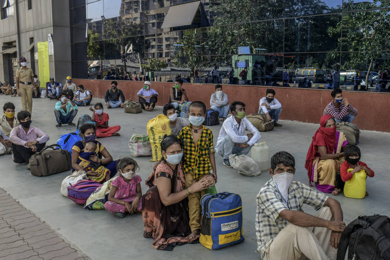 Famílias de migrantes esperam para embarcar em um trem de Mumbai para suas cidades natais no estado de Uttar Pradesh