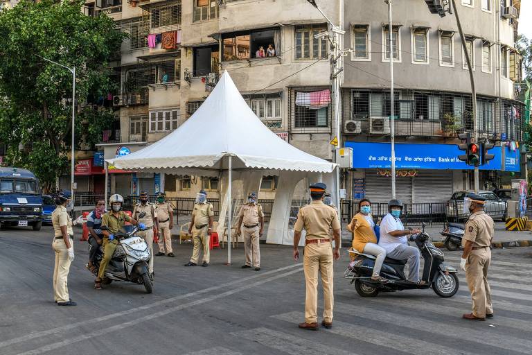 Policiais em posto de controle monitoram bloqueio imposto por quarentena na cidade