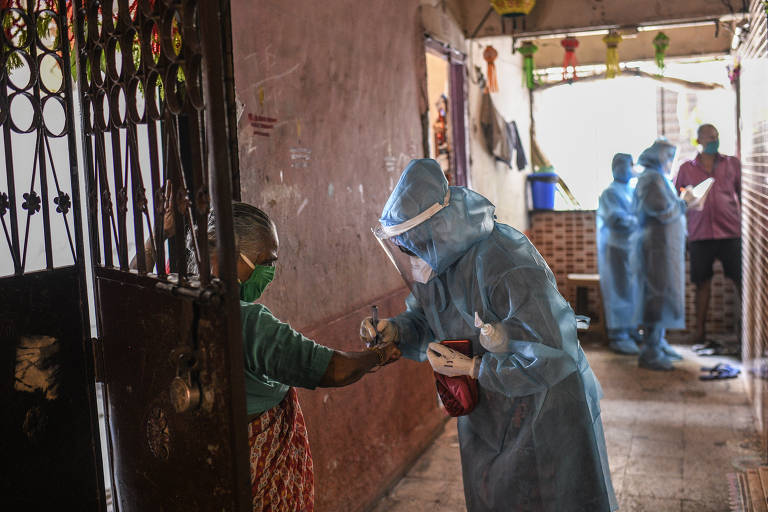 Profissionais de saúde marcam moradora após ela entrar em contato com um paciente contaminado com coronavírus na favela de Dharavi