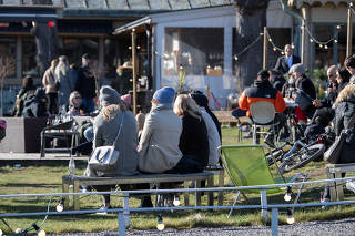 People enjoy the sunny weather at an outdoor restaurant at Djurgarden, as the coronavirus disease (COVID-19) continues to spread, in Stockholm