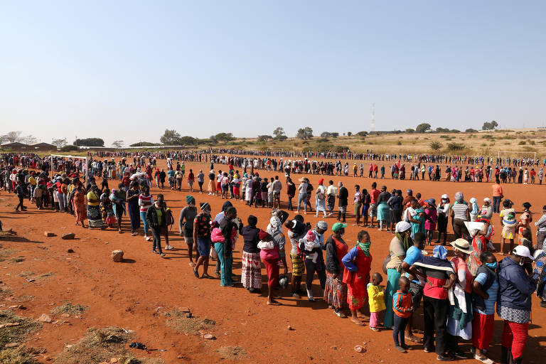 Em meio à pandemia de coronavírus, multidão aguarda em fila para receber comida em assentamento próximo a Pretória, na África do Sul 