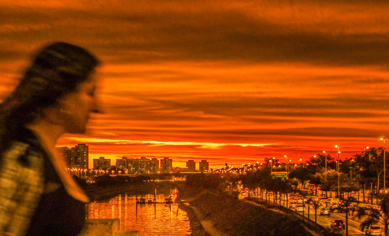 Mulher caminha em ponte sobre a marginal do rio Tietê