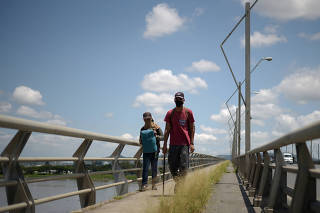 Two Venezuelan immigrants cross the National Unity Bridge on their way to Peru where family members can take them in, amid the spread of the coronavirus disease (COVID-19), in Guayaquil