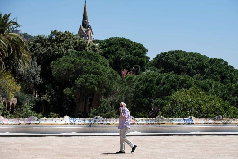 Homem com máscara caminha pelo parque Guell, em Barcelona, em 20 de maio; a cidade passou a permitir o acesso aos parques e praias