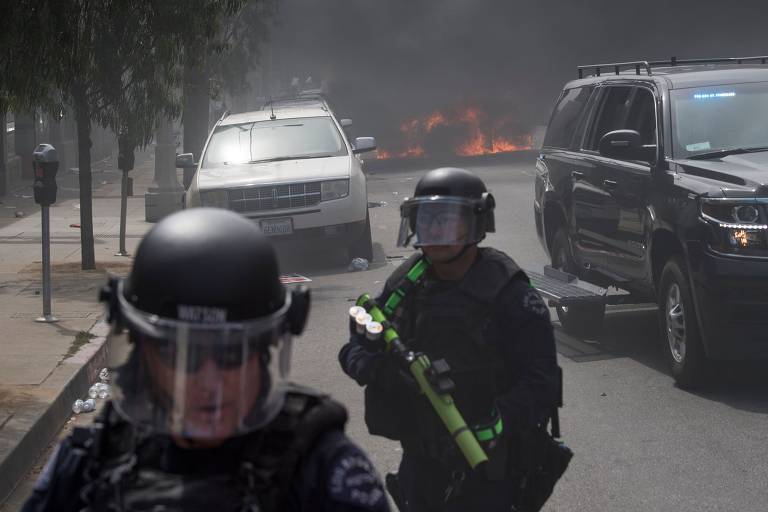 Agentes próximos a carro da polícia incendiado durante ato em Los Angeles