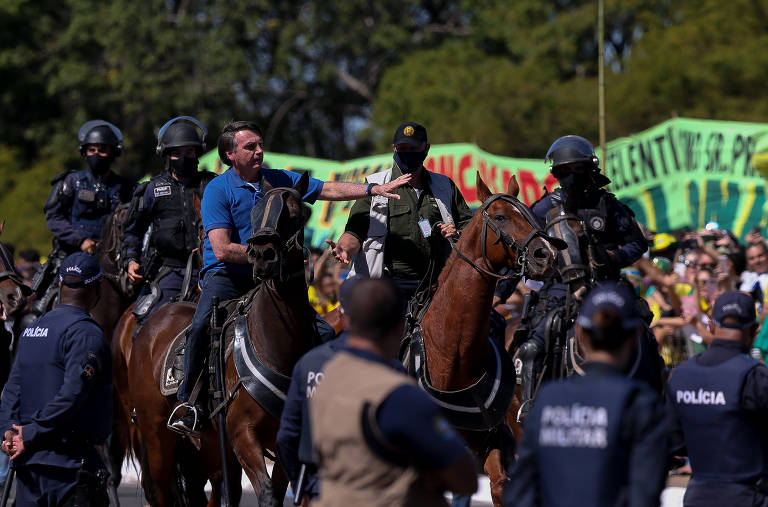 O presidente Jair Bolsonaro cavalga em frente de manifestantes em um cavalo da Polícia Militar durante manifestação em apoio ao governo