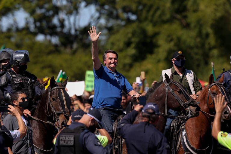 Montado em um cavalo da Polícia Militar, o presidente Jair Bolsonaro acena para apoiadores, durante ato em apoio ao  governo, em Brasília