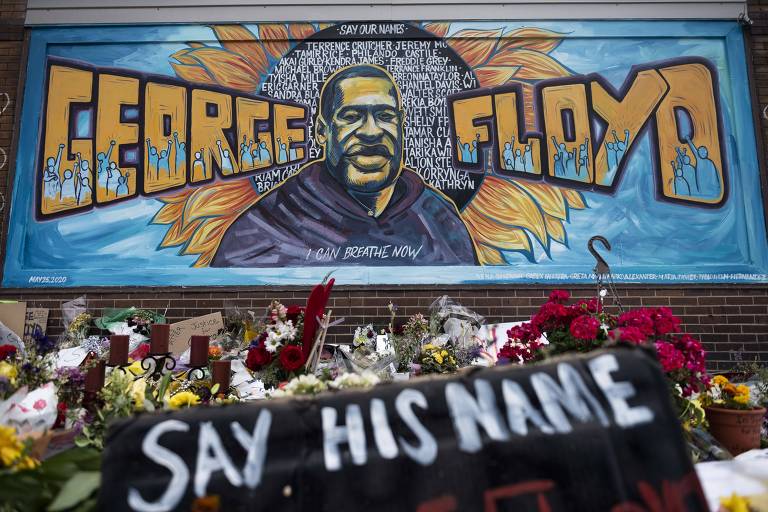 Muro pintado com o rosto de George Floyd, cheio de flores, no local em que ele foi morto pela polícia, em Minneapolis  