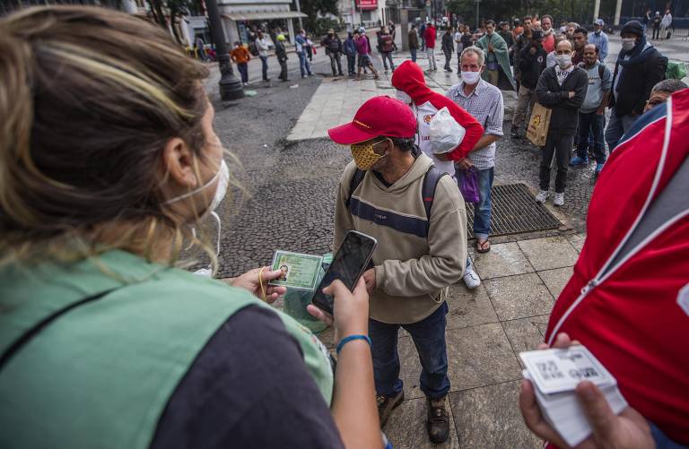 Fila de pessoas em situação de rua para receber um cartão do Bom Prato.