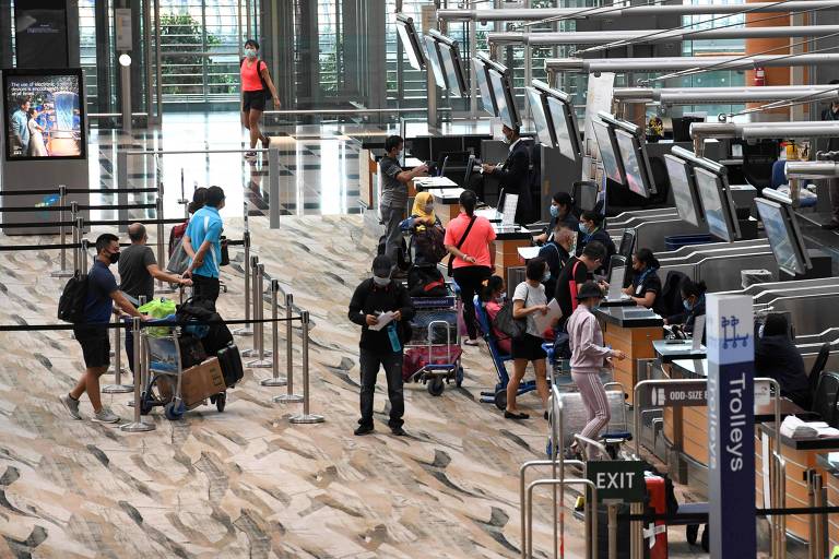 Passageiros fazem check-in no aeroporto de Singapura usando máscaras e respeitando o distanciamento de segurança