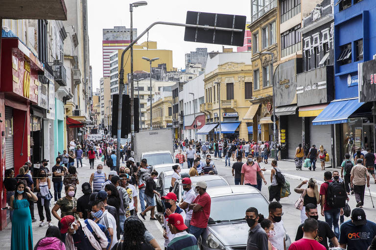 Consumidores e vendedores ambulantes circulam e aguardam para entrar nas lojas, na região da 25 de Março.