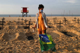 An activist of the NGO Rio de Paz wearing a protective mask attends a demonstration during which one hundred graves were dug on Copacabana beach symbolising the dead from the coronavirus disease (COVID-19), in Rio de Janeiro