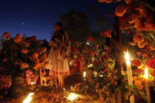 Woman stands near a relative's grave on the Day of the Dead, at a cemetery in Santa Maria Atzompa, in the Mexican state of Oaxaca