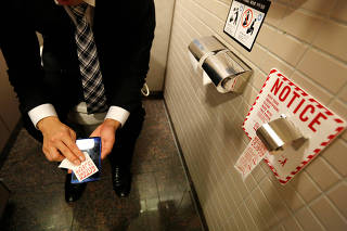 Man demonstrates a toilet roll for wiping smartphones, installed by Japanese mobile phone company NTT Docomo, in a high-tech bathroom equipped with bidet and heated seat at Narita international airport in Narita