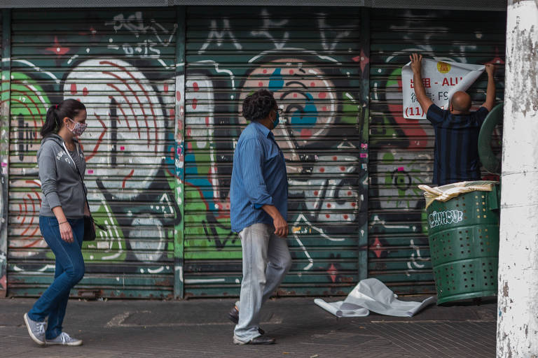 Homem coloca placa de "aluga-se" na região central de São Paulo.