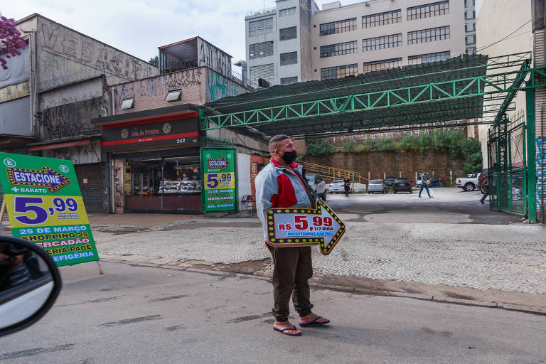 Homem-placa tenta atraír motoristas em estacionamento na região da 25 de Março.
