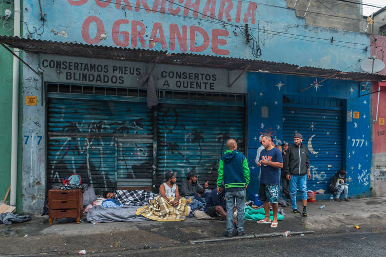 Pessoas em situação de rua ocupam a marquise de uma borracharia fechada na rua Javaés, no Bom Retiro.