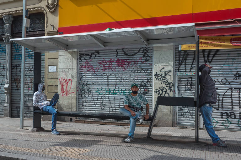 Homens são vistos em ponto de ônibus na rua Coronel Xavier de Toledo, na região central da cidade.