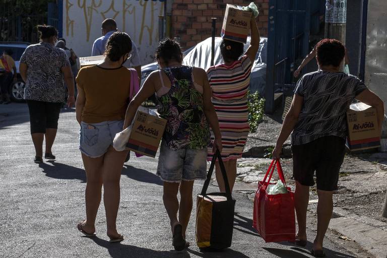 Mulheres carregando caixas e sacolas com alimentos que receberam do movimento de moradores. 