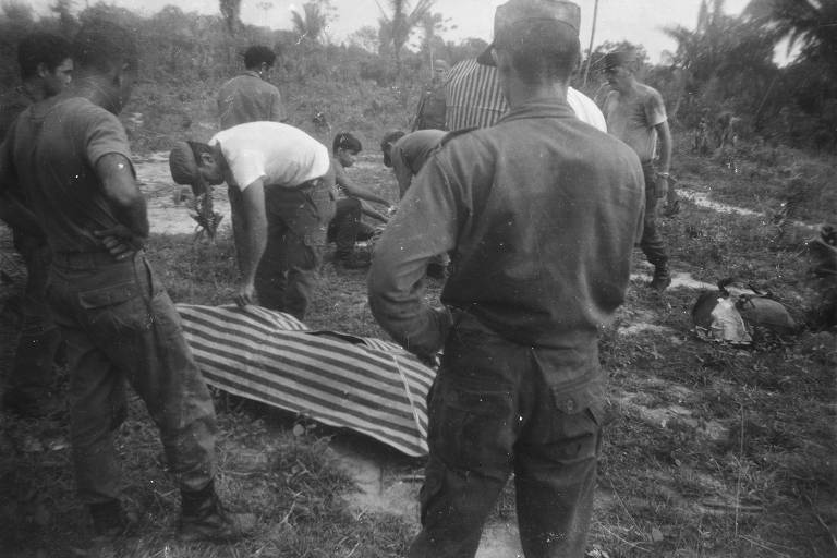 Corpos de guerrilheiros são embalados em lonas listradas por militares, em 1972, na região próxima às margens do rio Araguaia, no estado Pará