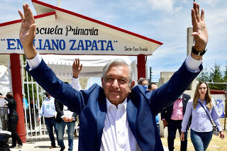 Mexico's President Andres Manuel Lopez Obrador gestures whilst arriving to a school for an event, in San Agustin Tlaxiaca
