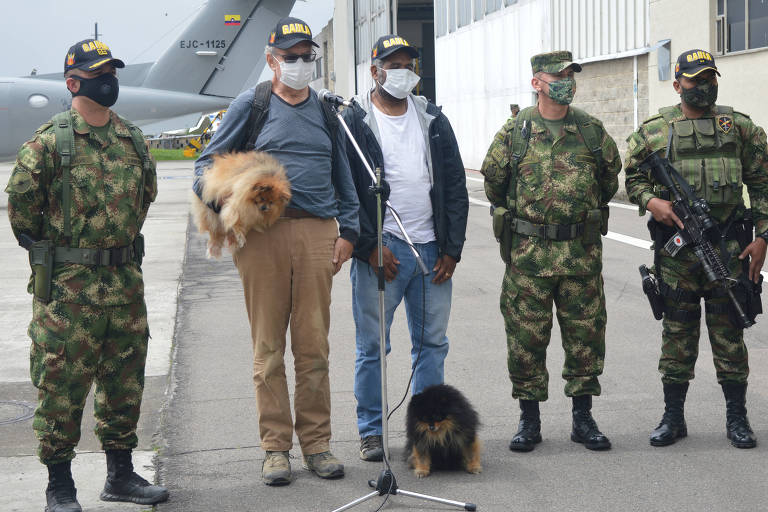 O suíço Daniel Max Guggenheim, segurando o cachorro, e o brasileiro José Ivan Albuquerque durante entrevista coletiva na base militar de Bogotá
