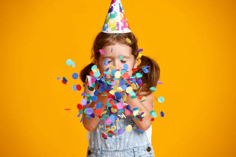 happy birthday child girl with confetti on  colored yellow background