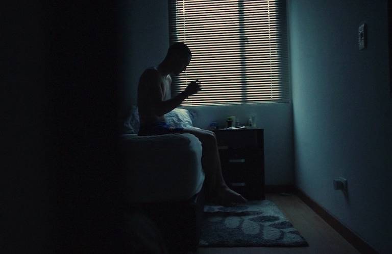 homem sentado num quarto escuro