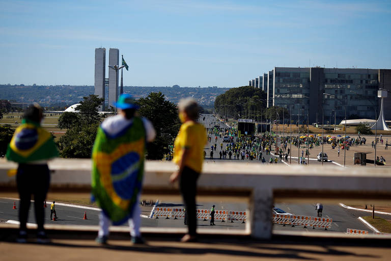 Manifestantes a favor de Bolsonaro observam ato na Esplanada dos Ministérios, em Brasília