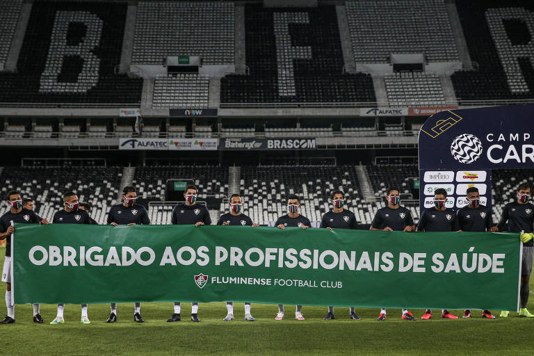 Jogadores do Fluminense com faixa de apoio aos profissionais de saúde antes da partida contra o Volta Redonda