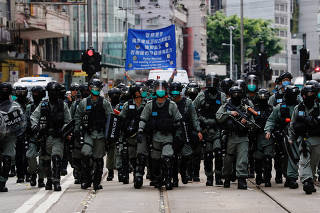 Riot police officers walk as anti-national security law protesters march during the anniversary of Hong Kong's handover to China from Britain, in Hong Kong