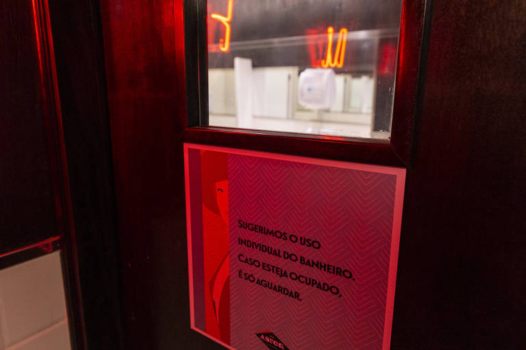 Placa no banheiro sugere uso individual do banheiro no Bar Astor.