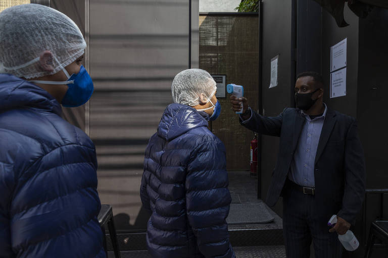 Funcionário do restaurante Loup mede temperatura de entregadores de gelo na entrada do estabelecimento.