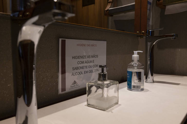 Placa no banheiro lembra da higienização das mãos.