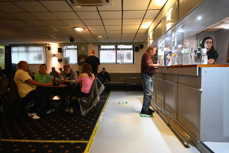 Marcações no chão e mesas afastadas auxiliam os clientes do Ridge Hill Working Men's Club, em Stalybridge, a manter o distanciamento social na reabertura do bar