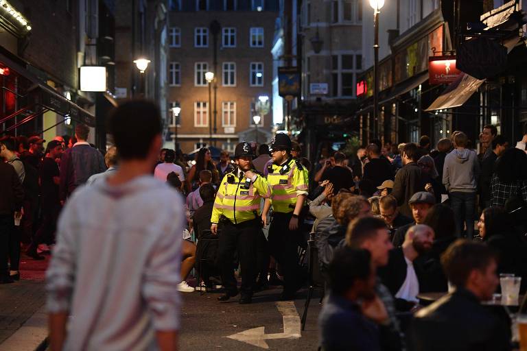 Policiais fazem ronda em meio a aglomeração de frequentadores em pubs da região do Soho, em Londres