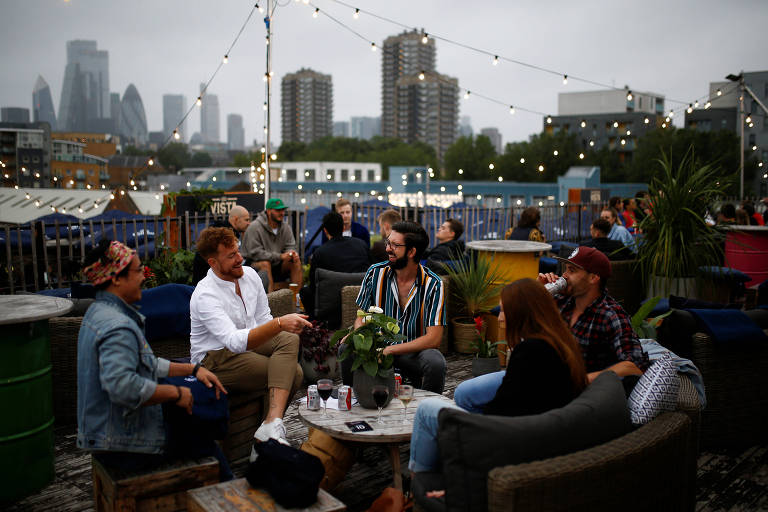Pessoas conversam em mesas ao ar livre do Skylight Bar, de Londres, no entardecer deste sábado
