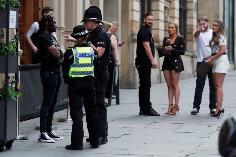 Policial aborda pedestre do lado de fora d eum pub recém aberto, em Newcastle