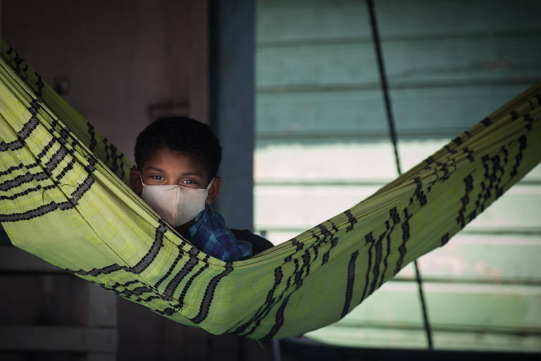 Garoto usa máscara de proteção em barco no rio Juruá; reportagem encontrou a maior parte da população nos vilarejos ribeirinhos da cidade de Juruá, Amazonas, usando o artefato de proteção