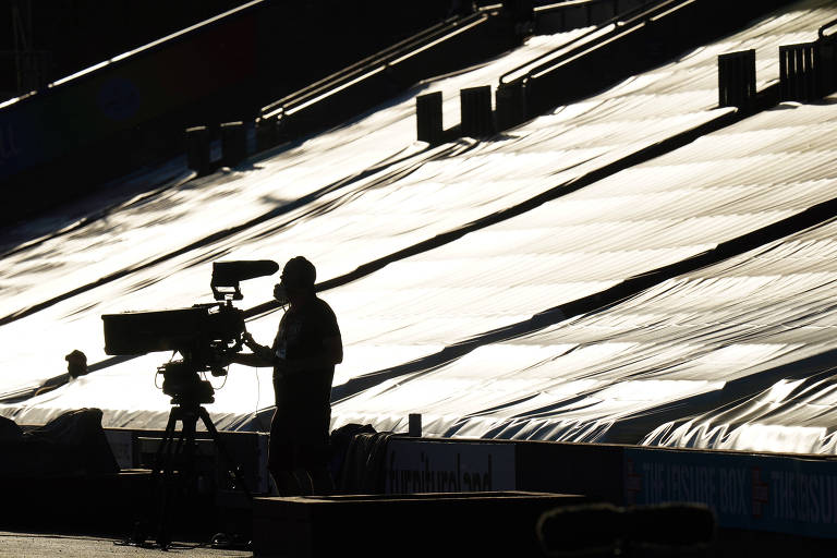 Operador de câmera em jogo da Premier League entre Burnley e Watford, com portões fechados