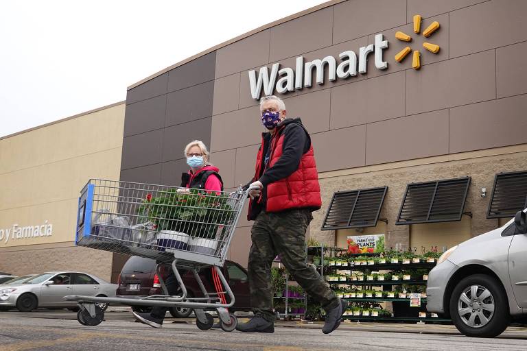 Home e mulher empurram carrinho em estacionamento de supermercado do Walmart