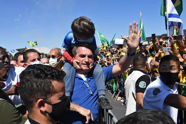 Jair Bolsonaro carrega criança em meio a encontro com seus apoiadores, em Brasília, no dia 31 de março, durante a pandemia do coronavírus