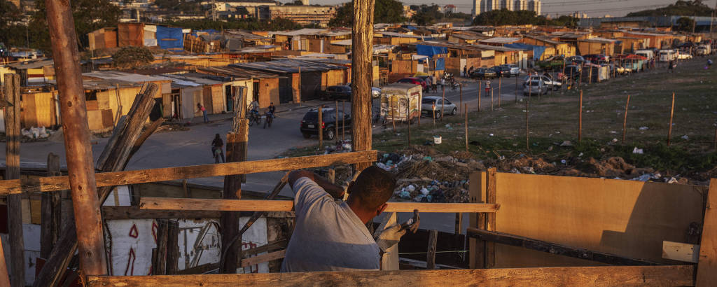 Morador trabalha na construção de barraco em terreno ocupado no Parque Novo Mundo