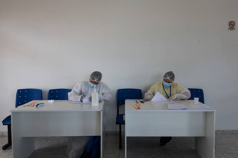 A dentista Karina Gonzaga, 30, e a técnica de saúde bucal, Alessandra da Silva, 37, fazem triagem de passageiros do aeroporto que podem ou não entrar em Carauari, no Amazonas