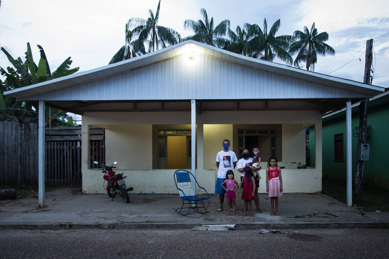 Adonildo Alves de Oliveiras, 46, ao lado da cadeira de balanço do pai, o pastor José Amâncio, morto por Covid-19, da esposa, Patricia Souza, 24 e das filhas Lara, Krislaine, Kaindra e Kaleli em Carauari (AM)