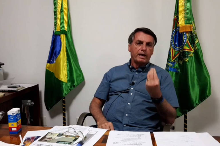 O presidente Jair Bolsonaro, sentado e gesticulando, durante live 