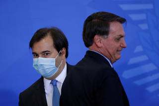 President of Brazil's Lower House Rodrigo Maia is seen next to Brazil's President Jair Bolsonaro during an inauguration ceremony of the new Communications Minister Fabio Faria (not pictured) at the Planalto Palace, in Brasilia