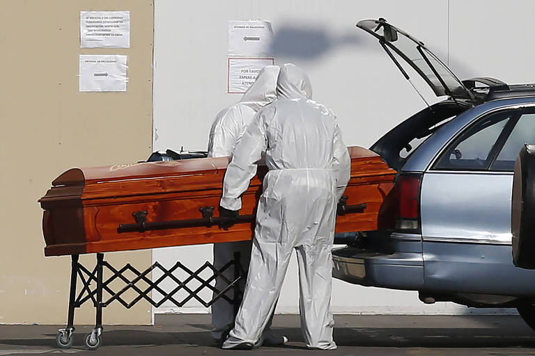 Funcionários de casa funerária em Santiago, no Chile, colocam caixa de vítima da Covid-19 em carro