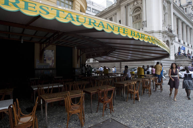 Fachada do Restaurante Bar Amarelinho, na Cinelândia, no Rio de Janeiro (RJ), com cadeiras na calçada e movimentação de pessoas