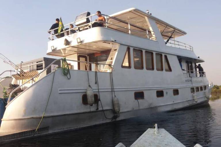 A lancha Arafat, que participou de pescaria ilegal e foi usada em operação policial no rio Abacaxis; trata-se de um barco branco, está num rio de águas marrons